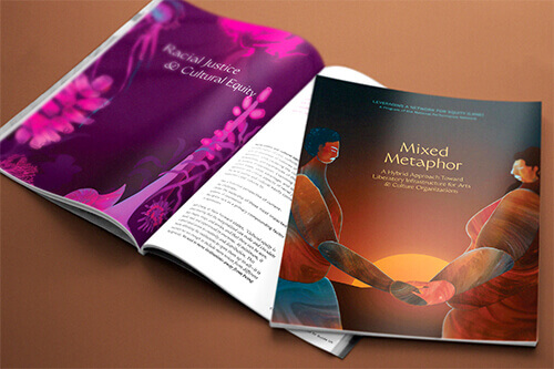 On a brown surface, the LANE workbook lies open on a spread in which the words 'Racial Justice & Cultural Equity' are situated in the middle of a deep fuchsia background, framed by both lush and spiny pink and purple sea vegetation and shells. On top of this spread is a closed workbook with a cover that shows two dark and medium-brown skinned people holding hands with their eyes closed. The sun sets between their canyon-textured bodies, revealing the words 'Mixed Metaphor.'